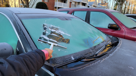 지난 4일 아침 둘루스의 아파트에서 한 한인이 밤새 얼어붙은 자동차 앞 유리창을 긁개로 긁어내고 있다