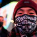 뉴욕 타임스퀘어에서 '아시아인 혐오를 멈춰라'라는 문구가 적힌 마스크를 쓴 한 남성이 지하철 앞에서 노숙자에게 밀쳐 숨진 미셸 고를 위한 촛불집회에 참석하고 있다. January 18, 2022. REUTERS/Jeenah Moon
