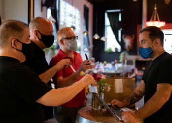 필라델피아 레스토랑 "Martha"에서 마스크를 쓴 고객들이 코로나 백신 접종 증명서를 보여주고 있다 . REUTERS/Hannah Beier/File Photo