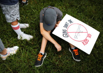 2022년 6월 11일 플로리다주 파크랜드에서 총기 규제 를 위한 집회에서 한 소년이 "총은 죽지 않고 아이들은 죽는다"라고 적힌 플래카드를 들고 있다. 사진 / 로이터