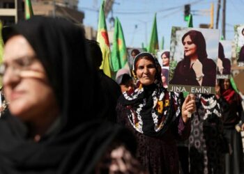 2022년 9월 26일 시리아 북동부 쿠르드족 통제 도시 카미슐리에서 22세 쿠르드족 여성 마흐사 아미니의 죽음에 항의하는 여성들이 깃발과 사진을 들고 시위를 벌이고 있다. 로이터 사진.