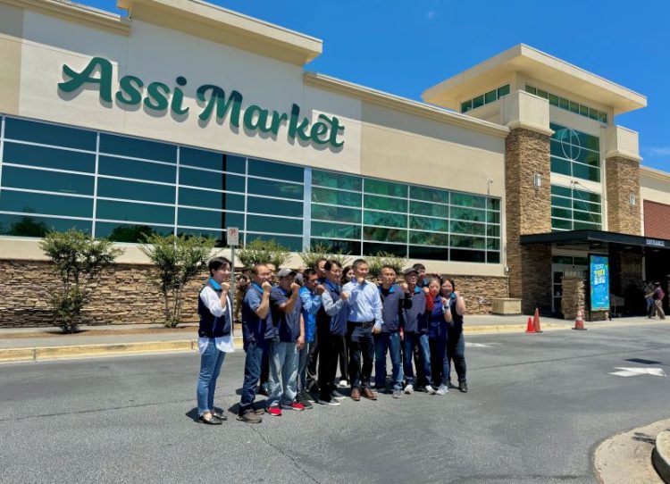 2024년 아씨마켓 관계자들이 새로 바뀐 간판 앞에서 파이팅을 외치고 있다. 윤지아 기자.