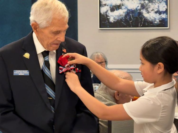 한인 어린이가 한국전 미군 참전용사에게 감사의 마음을 담아 꽃을 달아주고 있다.