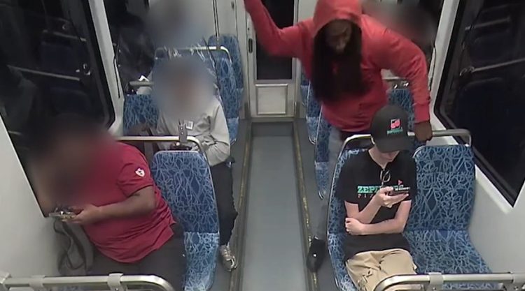 빨간 후드티를 입은 용의자가 주머니칼을 깨너들고 앞에 앉아 있는 피해자의 목을 찌르는 모습. [보안영상 캡처]
