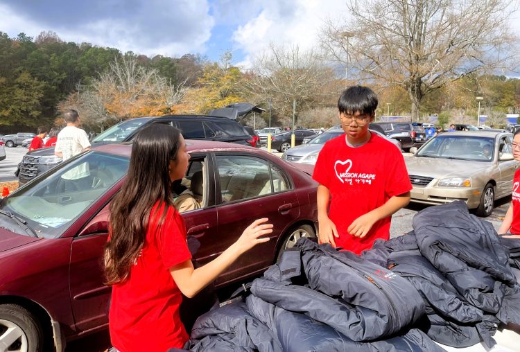 지난 22일 사우스디캡 몰에서 미션아가페 봉사자들이 사랑의 점퍼를 배포하고 있다.