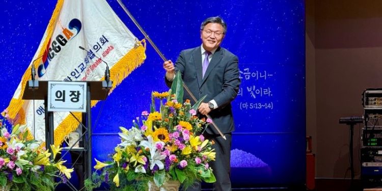 손정훈 신임 회장이 교협기를 받아 흔들고 있다.  윤지아 기자.