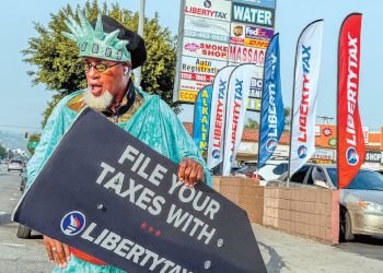 세금보고 시즌을 알리는 리버티 택스 ‘웨이버’가 LA한인타운 웨스턴 애비뉴에서 가게 안내 표지판을 들고 홍보 활동을 벌이고 있다. 김상진 기자