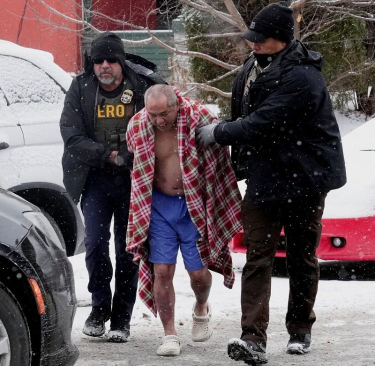 지난 18일 이민단속 요원들이 미네소타주 세인트 폴의 한 주택에 진입해 영하의 날씨에도 불구, 겉옷을 입지 않은 한 남성을 연행하고 있다. [로이터]