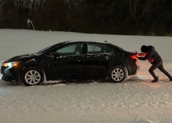 오클라호마주 털사에서 눈이 쌓인 도로에 갇힌 자동차를 운전자가 밀고 있다. [로이터]