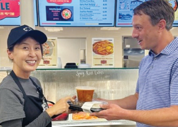 크로거 마켓 휴스턴 지점에 개장한 한식 델리 ‘라이언스 스트리트 테이블’의 스테이시 권(왼쪽) 대표가 백인 고객에게 김치찌개와 반찬을 건네고 있다. [라이언스 스트리트 테이블 제공]