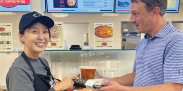 크로거 마켓 휴스턴 지점에 개장한 한식 델리 ‘라이언스 스트리트 테이블’의 스테이시 권(왼쪽) 대표가 백인 고객에게 김치찌개와 반찬을 건네고 있다. [라이언스 스트리트 테이블 제공]