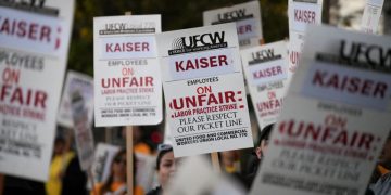 지난 2월 9일 캘리포니아주 로스앤젤레스의 카이저 퍼머넌트 병원 앞에서 카이저 퍼머넌트 약국 및 검사실 직원들이 "부당 노동 행위 파업"에 항의하는 피켓 시위를 벌이며 팻말을 들고 있다. [로이터]
