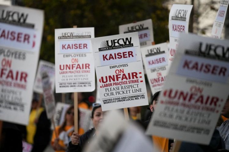 지난 2월 9일 캘리포니아주 로스앤젤레스의 카이저 퍼머넌트 병원 앞에서 카이저 퍼머넌트 약국 및 검사실 직원들이 "부당 노동 행위 파업"에 항의하는 피켓 시위를 벌이며 팻말을 들고 있다. [로이터]