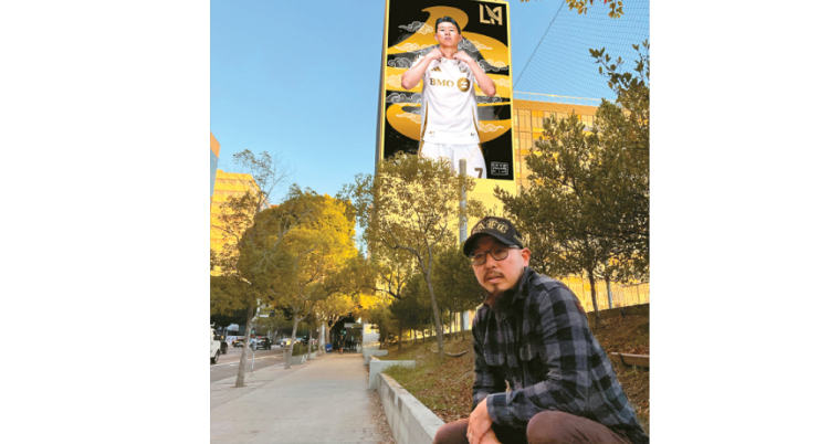 데이브 영 김씨가 자신이 LA 한인타운 내 코스비 빌딩 외벽에 그린 축구 스타 손흥민 대형 벽화 앞에 앉아 있다. [데이브 영 김 제공]