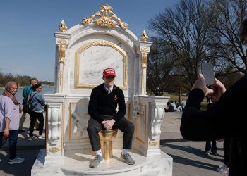 미국 워싱턴 D.C. 내셔널 몰의 링컨 기념관 인근에 전시된 '왕에게 어울리는 옥좌'라는 제목의 '황금 변기' 조형물 위에 MAGA(트럼프 지지 문구) 모자를 쓴 한 사람이 앉아 있다.″ [로이터]