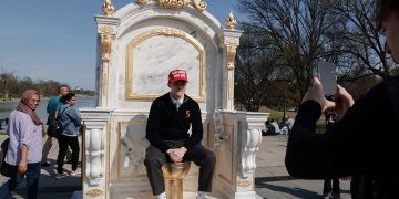 미국 워싱턴 D.C. 내셔널 몰의 링컨 기념관 인근에 전시된 '왕에게 어울리는 옥좌'라는 제목의 '황금 변기' 조형물 위에 MAGA(트럼프 지지 문구) 모자를 쓴 한 사람이 앉아 있다.″ [로이터]